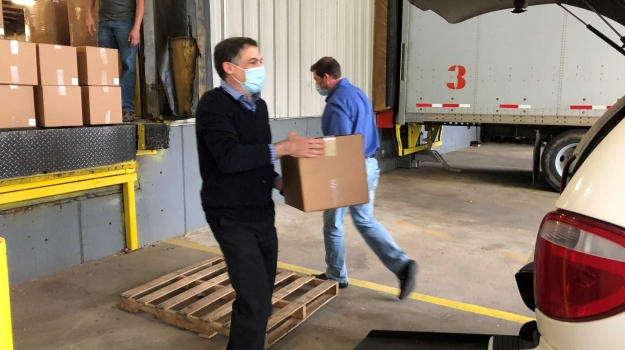 Jeff Slosman loads a box of wipes into a van for delivery